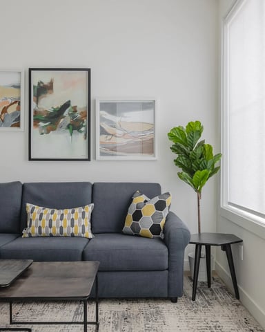 Modern open-plan living room with blue sofa, wooden coffee table, and kitchen visible in background