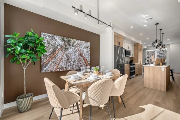 Open-plan kitchen and living room with white cabinetry, island seating, mauve accent wall, and grey sofa with colourful pillows